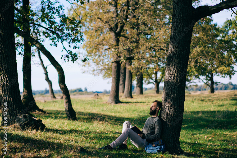 Bearded man hipster student reading a book and relax in park, exams Bearded man hipster student reading a book and relax in park, exams