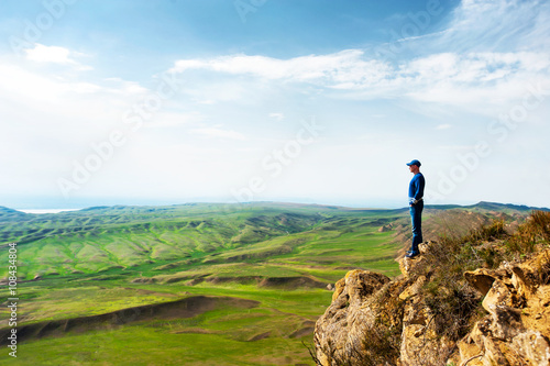 Young man look out to view at top of rock cliff. © AnnaElizabeth
