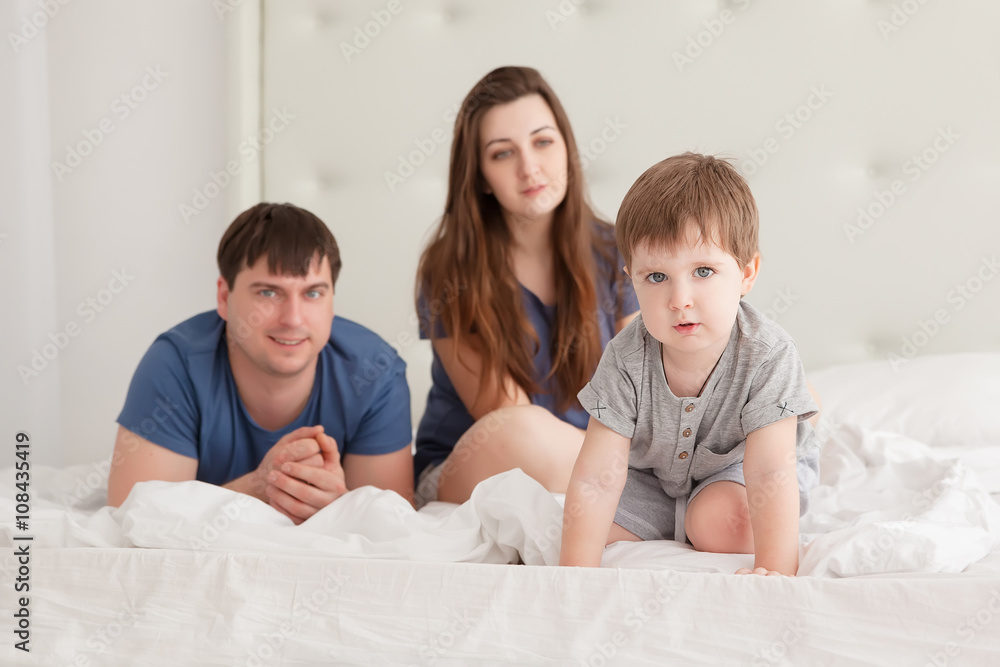 little boy and parents On Parents Bed Wearing Pajamas