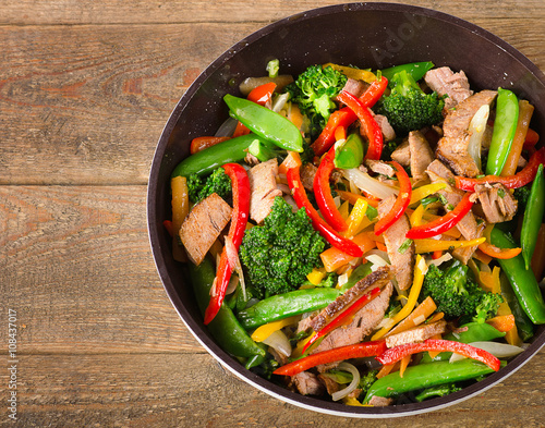 Fotografia, Obraz Beef and vegetables stir fry on a wooden table.
