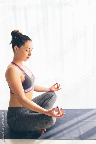 Guptasana. Beautiful yoga woman practice in a traning hall background. Yoga concept. photo