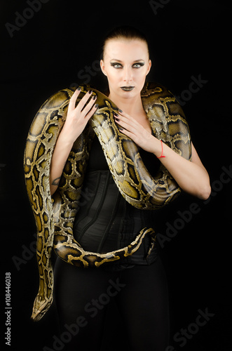 sexy brunette holding python over black background 