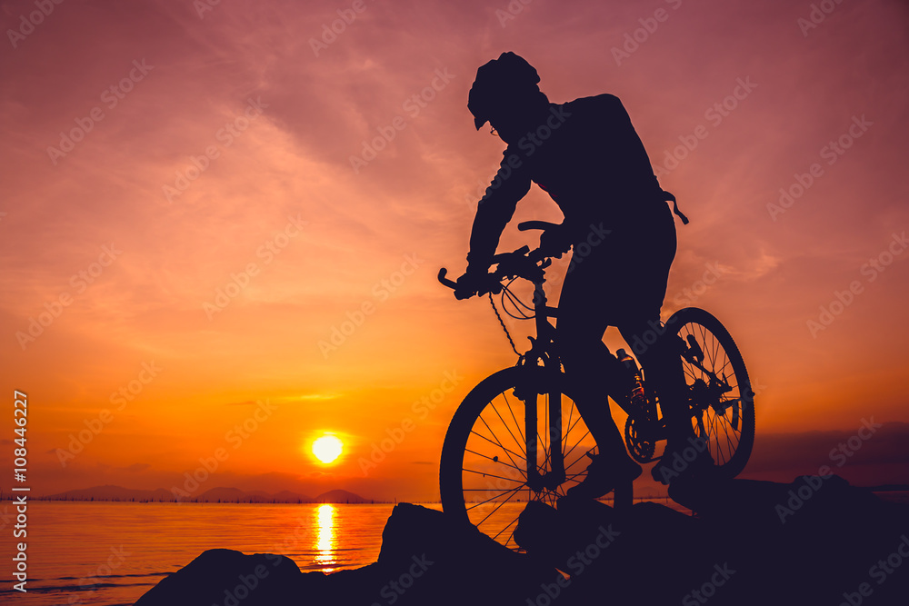 Fototapeta premium Healthy lifestyle. Silhouette of bicyclist riding the bike at seaside.