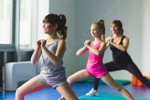 Fototapeta Naklejka Na Ścianę i Meble -  Girls and Instructor or mother doing gymnastic exercises  in fitness class