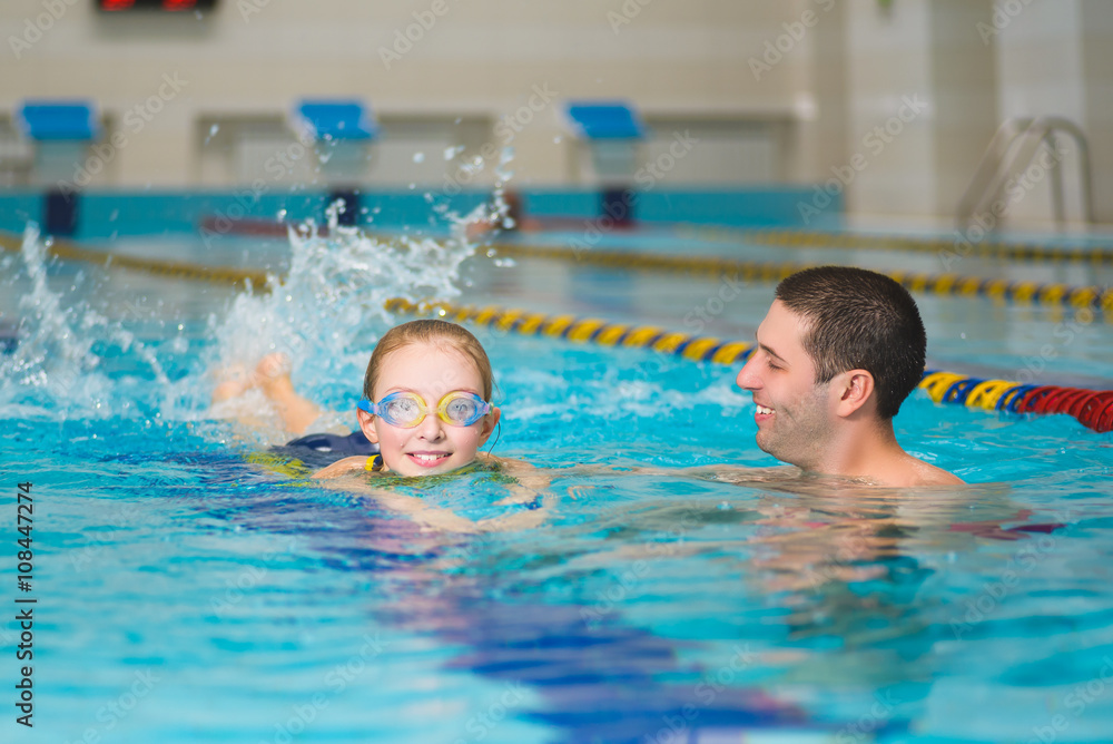 instructor teaches the girl swimming in a pool