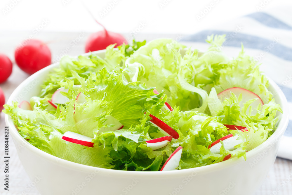 light diet salad with fresh lettuce and radish in a white bowl on wooden background, closeup light diet salad with fresh lettuce and radish in a white bowl on wooden background, closeup