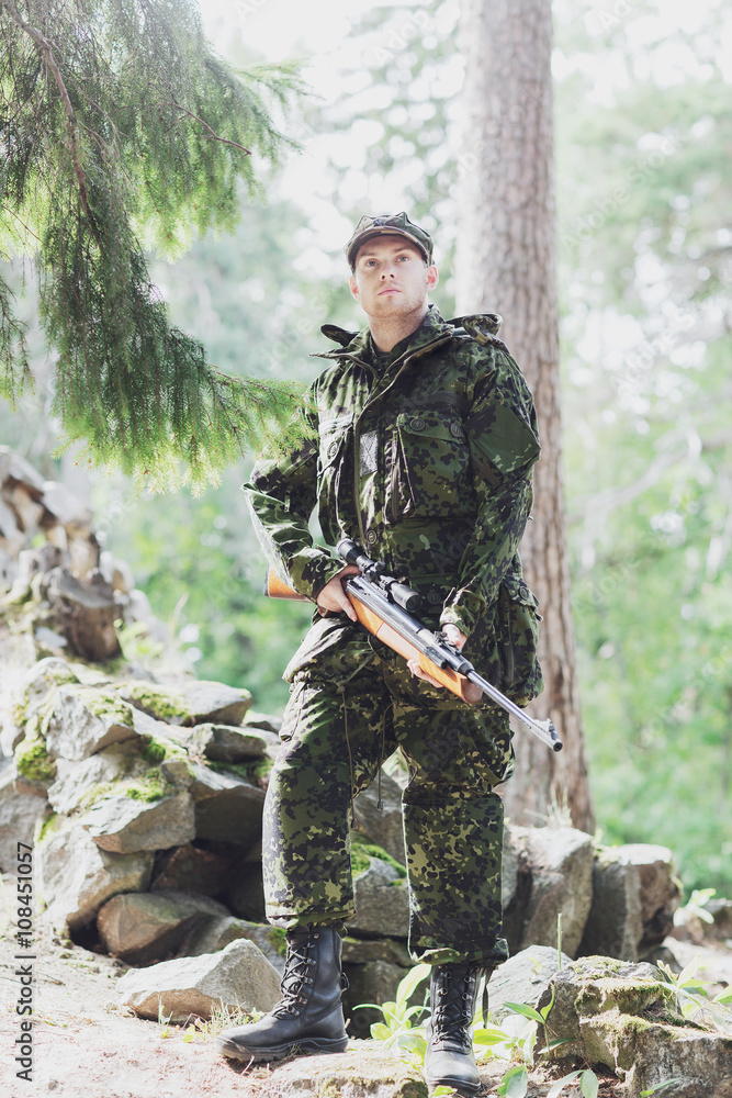 young soldier or hunter with gun in forest