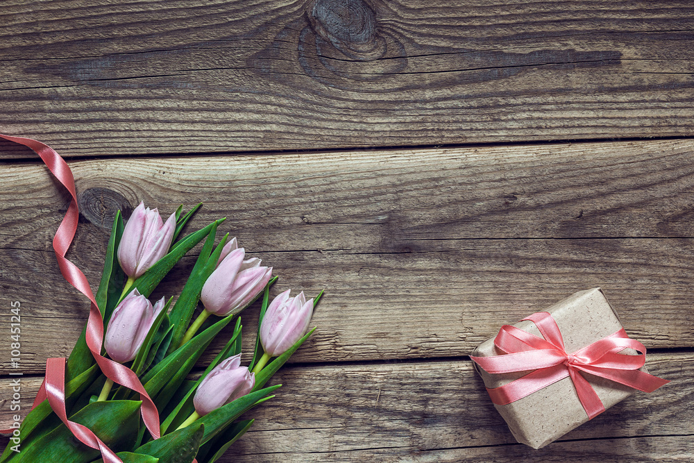Pink tulips and gift box with rosy ribbon on a grunge wooden ba Pink tulips and gift box with rosy ribbon on a grunge wooden ba