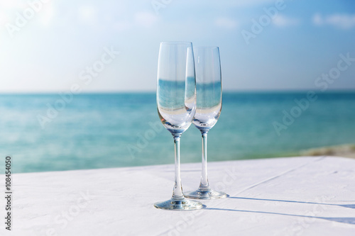  close up of two champagne glasses on beach 