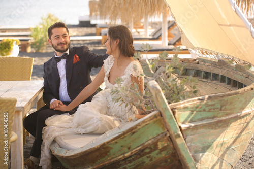 bride and groom relaxing on a wooden boat photo