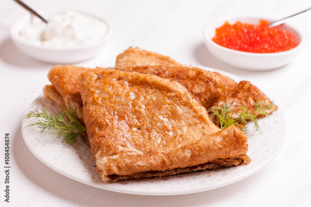 crepes with red caviar and sour cream, isolated on white crepes with red caviar and sour cream, isolated on white