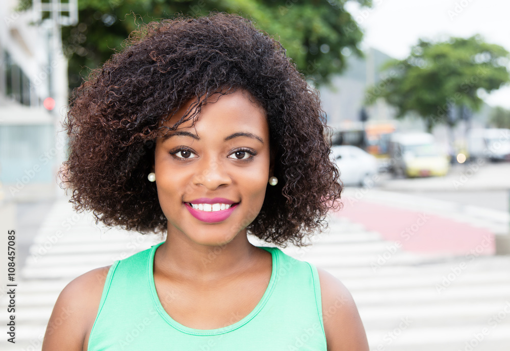 Fototapeta premium Lachende Afrikanerin mit Locken in der Stadt