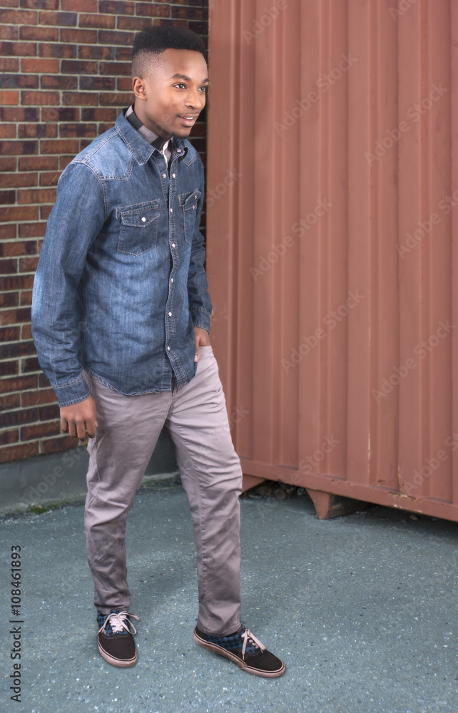 young man standing up outside near brick wall and container young man standing up outside near brick wall and container