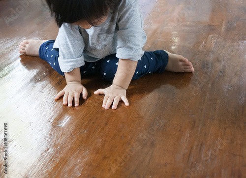 Baby is sitting on the wood floor photo