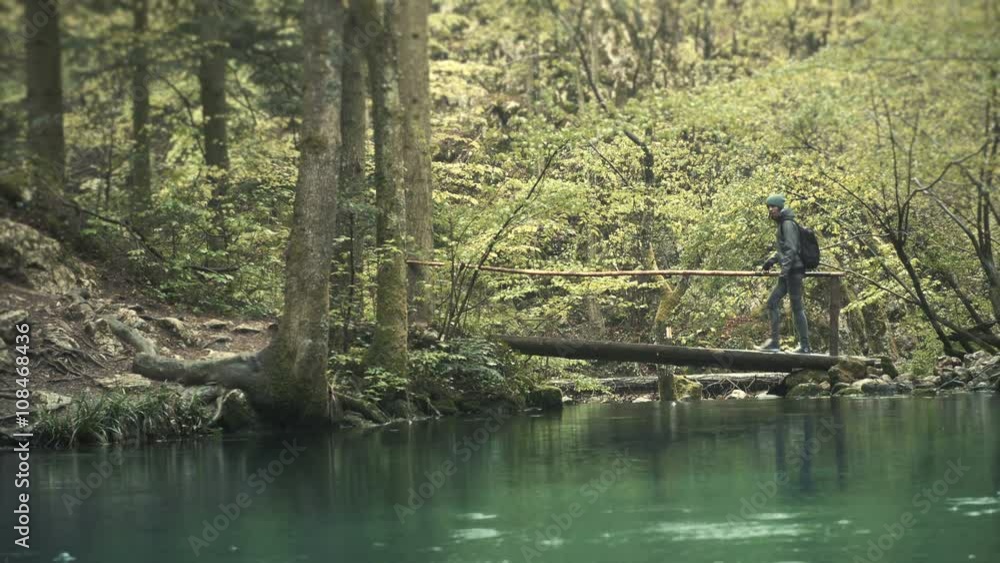 Women hiker walking on wooden bridge. Beautiful blue lake in the foreground Women hiker walking on wooden bridge. Beautiful blue lake in the foreground