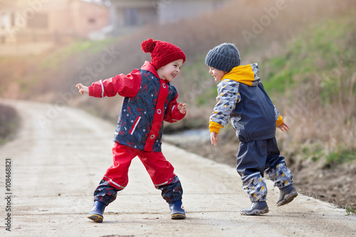 Two cute children, boy brothers, playing together in the park, r