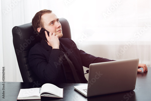 Young happy satisfied businessman calling with his mobile phone