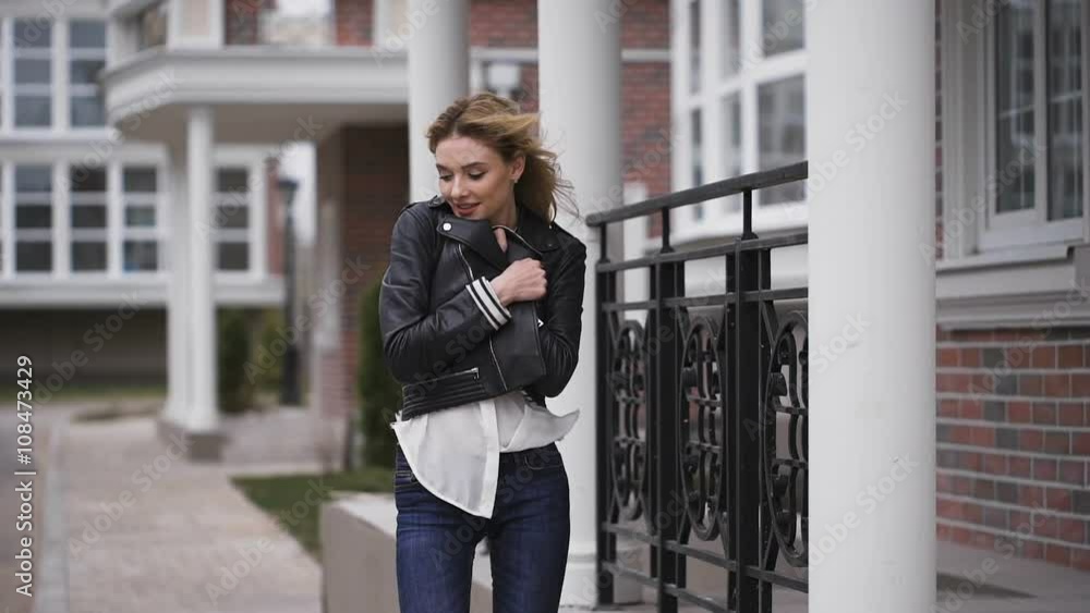 The blonde in a black leather jacket, smiling, to her a little bit cool. Around the house is made of brick. The blonde in a black leather jacket, smiling, to her a little bit cool. Around the house is made of brick.