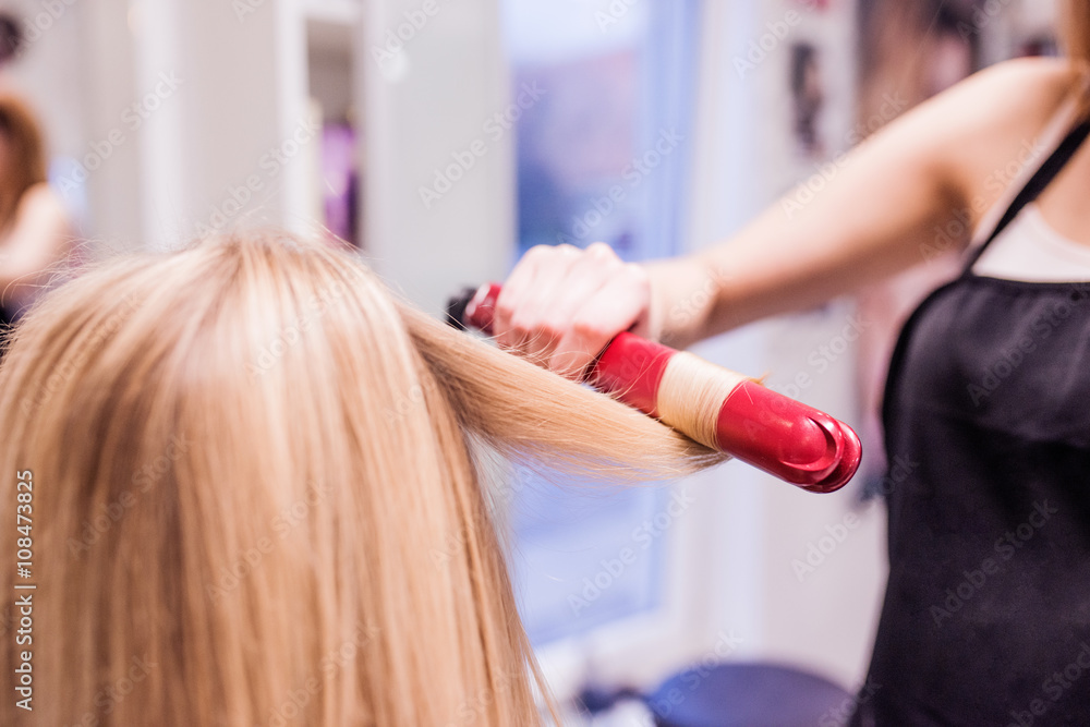 Unrecognizable hairdresser creating hairstyle for her beautiful Unrecognizable hairdresser creating hairstyle for her beautiful