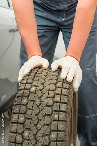 car tire and mechanic hand gloves closeup