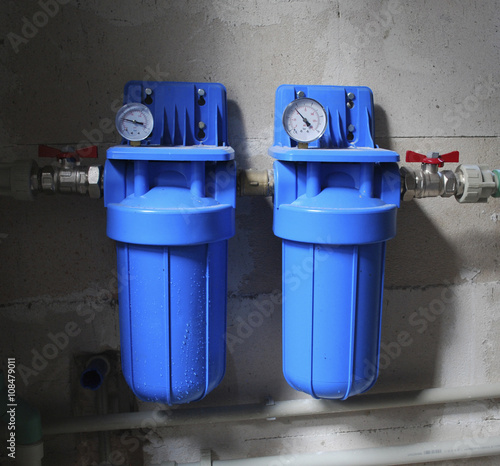 Two blue aqua filters with pressure meter. Set in a private home for purification of drinking water from wells. 