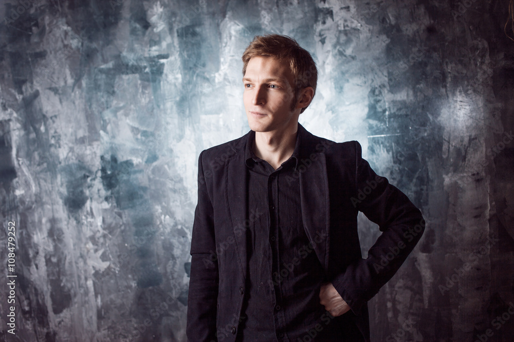 young man in black suit on textured grey background young man in black suit on textured grey background