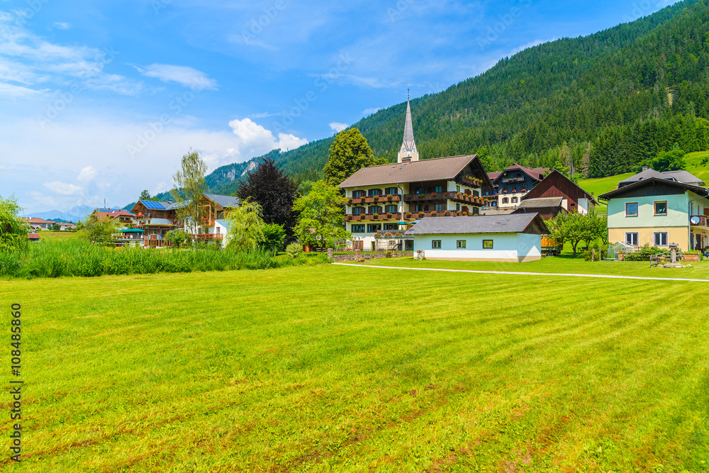 Traditional alpine houses on shore of Weissensee lake in summer landscape of Carinthia land, Austria