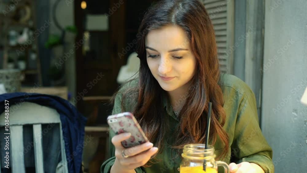 Thoughtful girl sitting in the cafe and texting on smartphone
Thoughtful girl sitting in the cafe and texting on smartphone