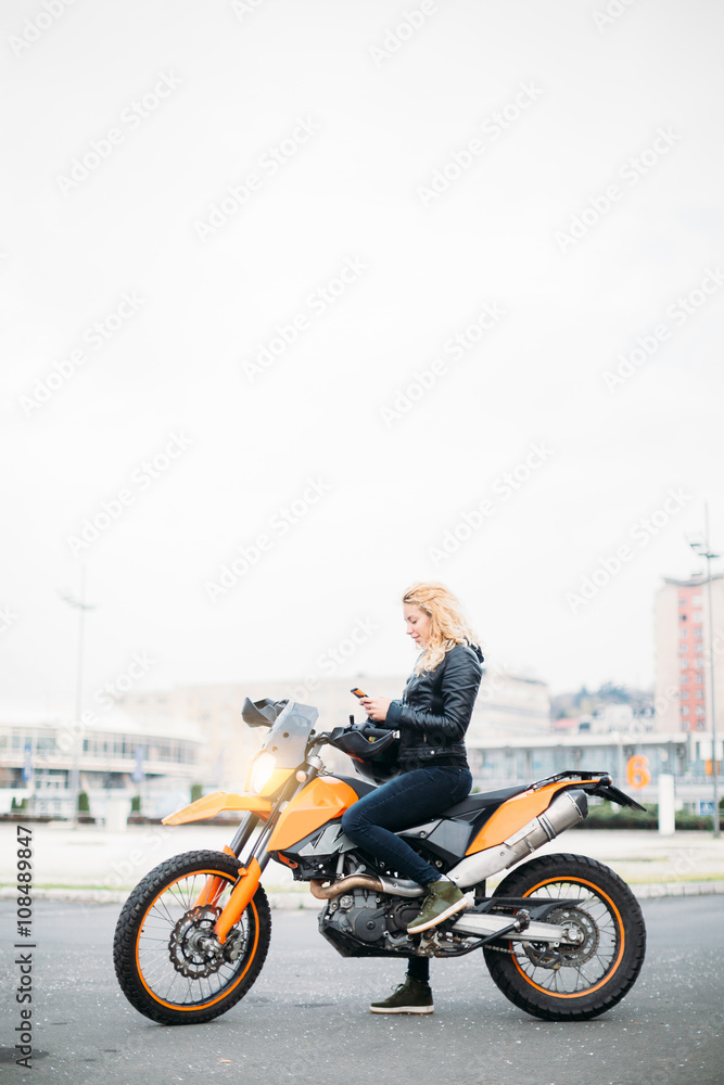 Young woman at motorcycle using mobile phone