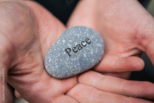 Fototapeta Inner balance concept: hands holding stones with the word peace
