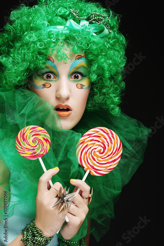 Girl with with creative make-up holds lollipop