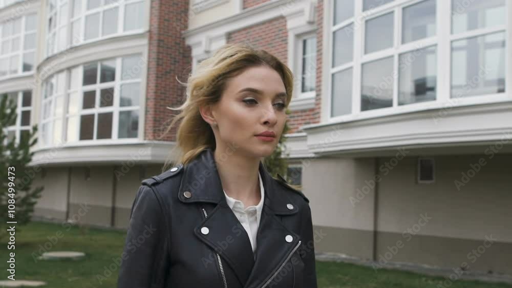 beautiful young woman walking on the street. Blonde confident gait moves the camera. City motif, an elite residential area. She personifies success. beautiful young woman walking on the street. Blonde confident gait moves the camera. City motif, an elite residential area. She personifies success.