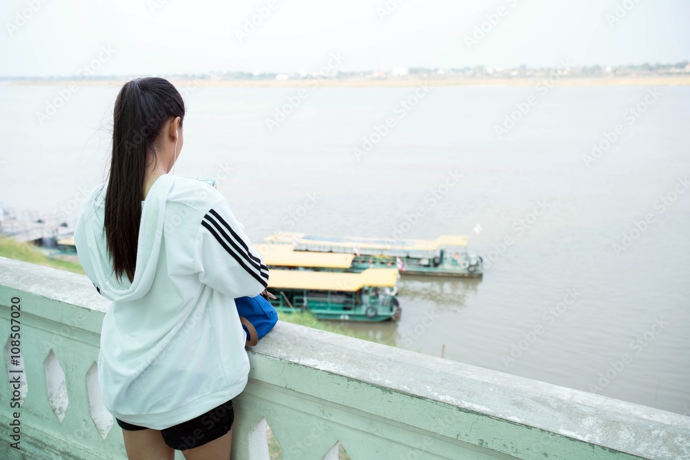 backside of Long hair woman looking down to Ferry, ferries at river, waterside  - lonely woman