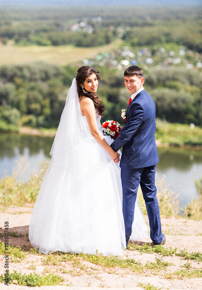 Bride and groom holding hands outdoors.