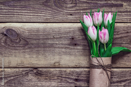 Background with bouquet of pink tulips in a brown paper on grung