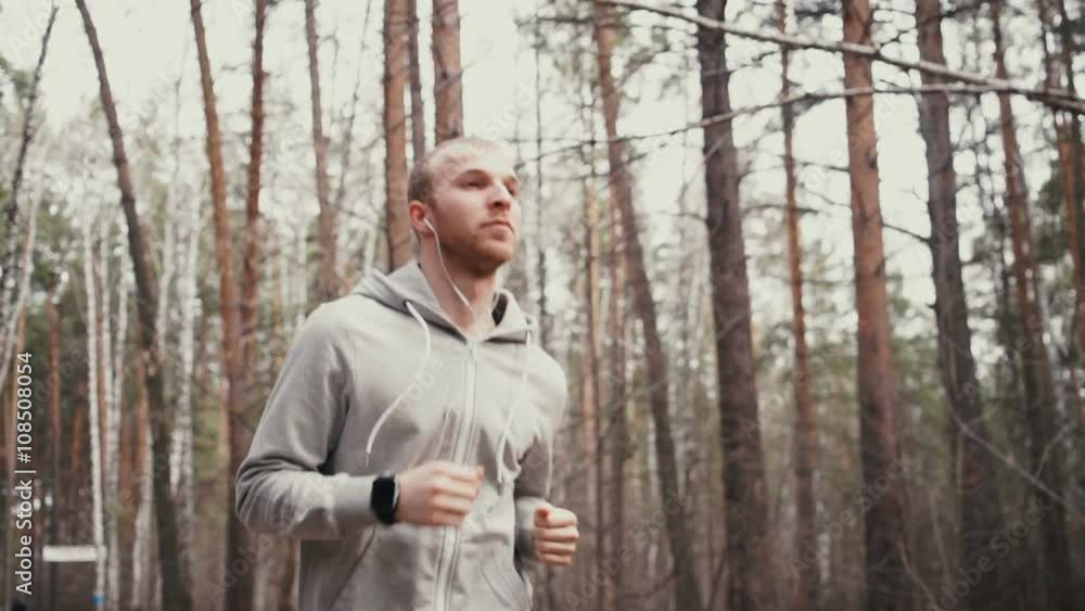 Man running in forest woods training and look at smart watches. Man running in forest woods training and look at smart watches.