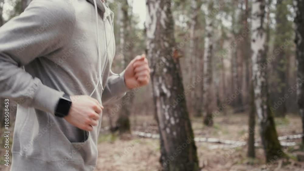 Man running in forest woods training and look at smart watches. Man running in forest woods training and look at smart watches.