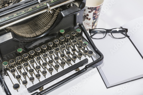 antique typewriter with coffe, a blank and a pencil on white background