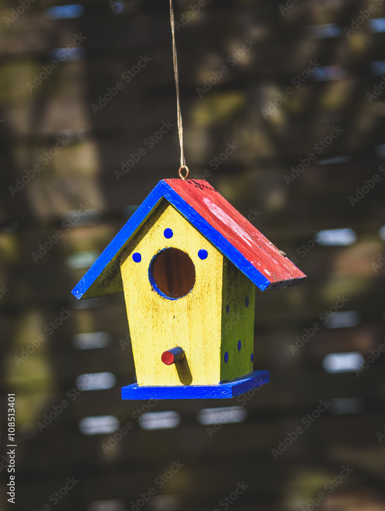 An old weathered DIY birdhouse hanging from the tree