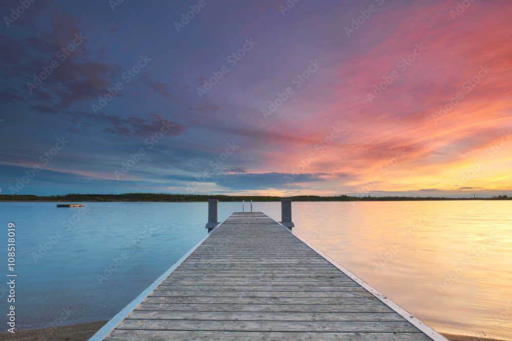 pastellfarbener Sonnenuntergang am Meer mit Holzsteg