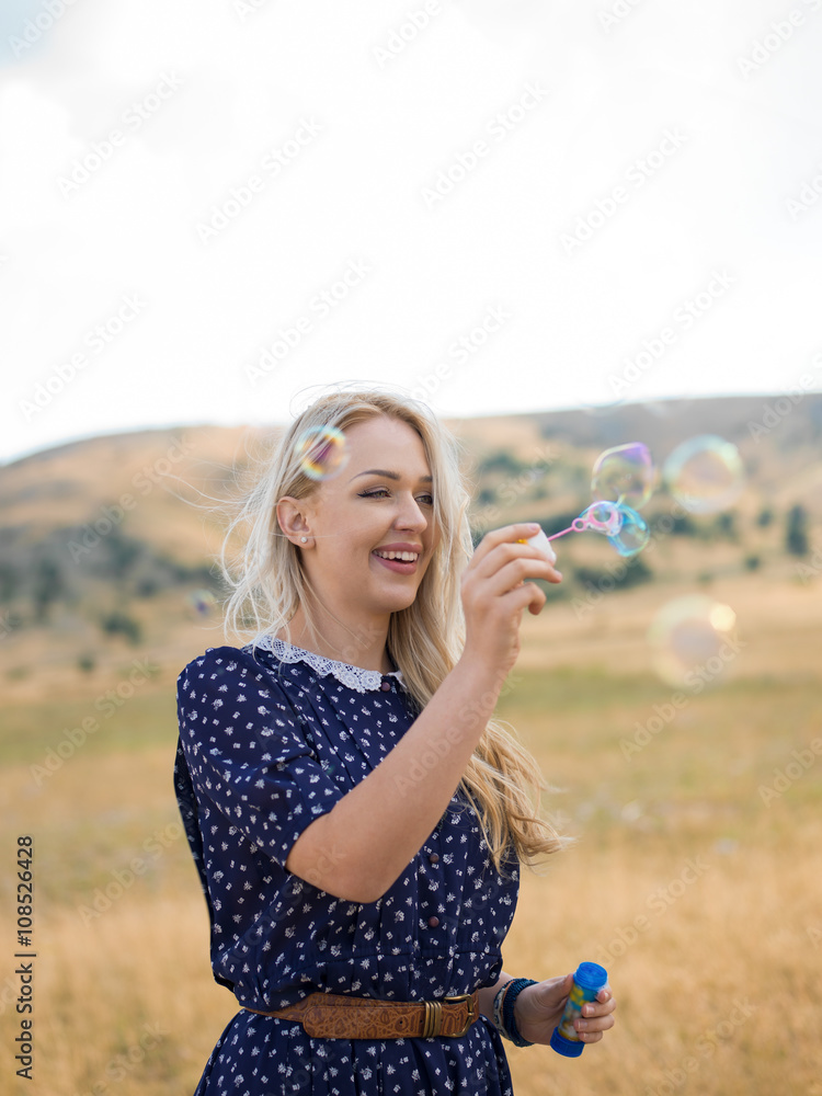 Portrait of a beautiful young woman blowing soap bubbles in the Portrait of a beautiful young woman blowing soap bubbles in the