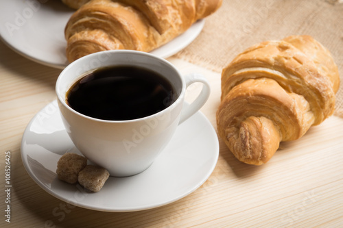 Fototapeta Naklejka Na Ścianę i Meble -  Croissants with cup of coffee on wooden background