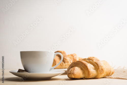 Fototapeta Naklejka Na Ścianę i Meble -  Croissants with cup of coffee on wooden background