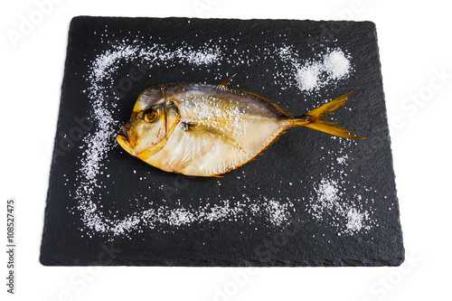 Dry fish on black stone. Isolated on white  background. photo