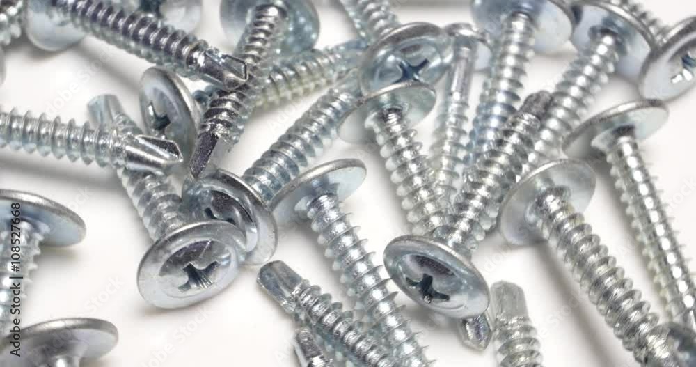 4k Close up of chrome crosshead screws rotating on a white background, looped video 4k Close up of chrome crosshead screws rotating on a white background, looped video