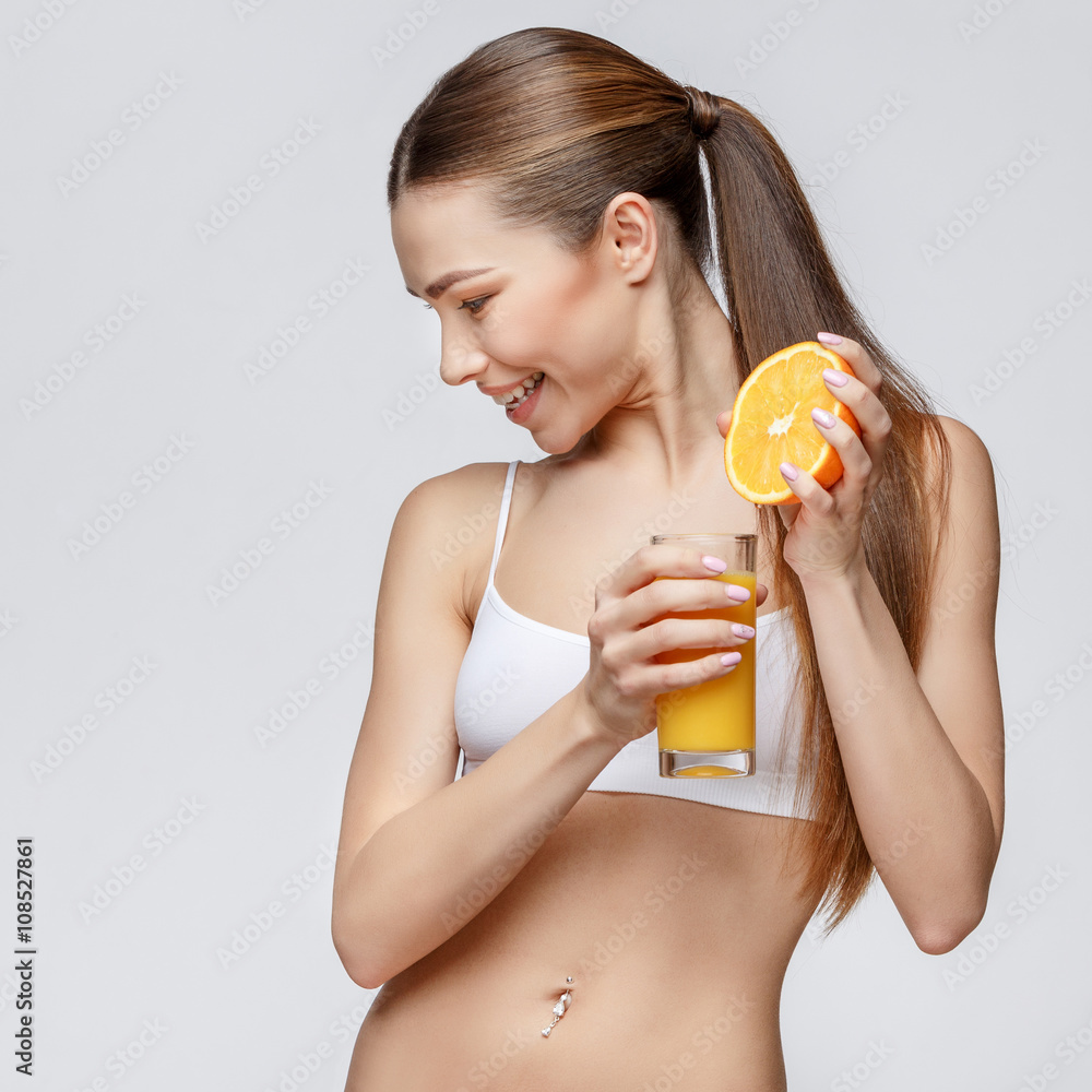 sporty woman over gray background holding glass of orange juice sporty woman over gray background holding glass of orange juice