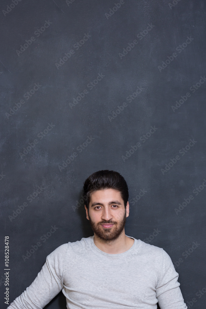 a young man with a beard on a chalkboard background with the emo