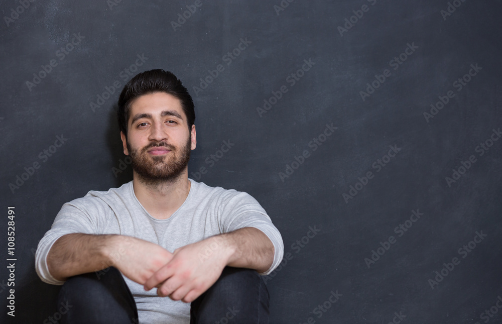 a young man with a beard on a chalkboard background with the emo