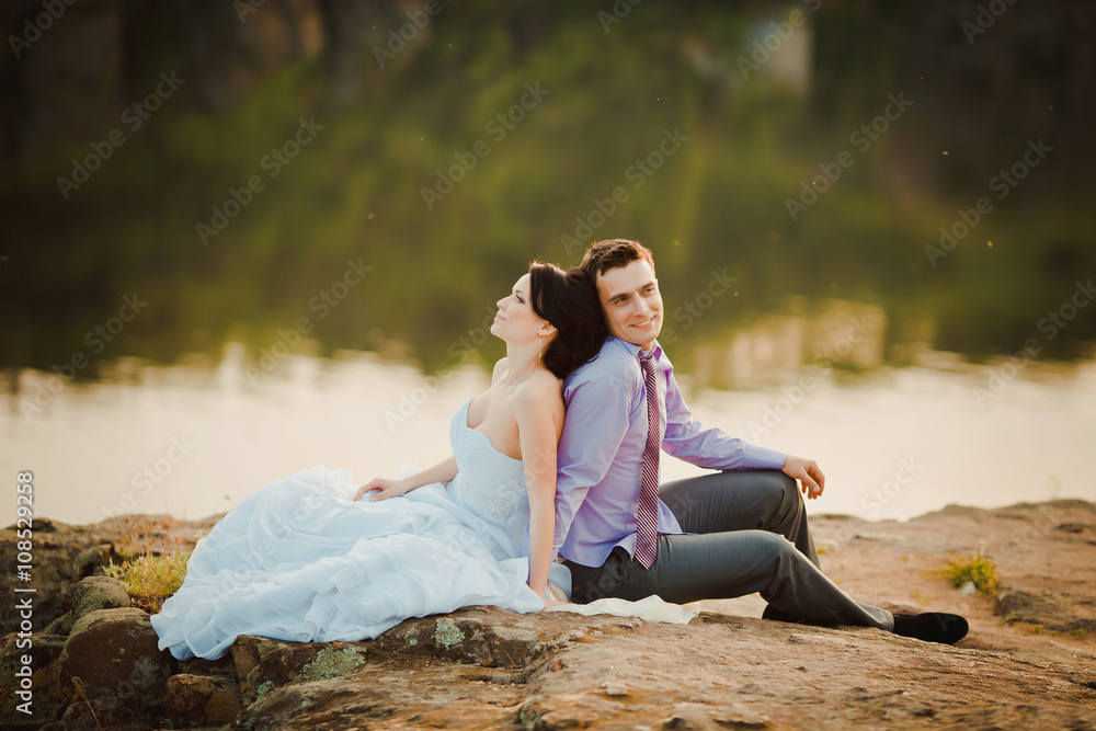 Happy bride and groom celebrating wedding day. Married couple sitting together