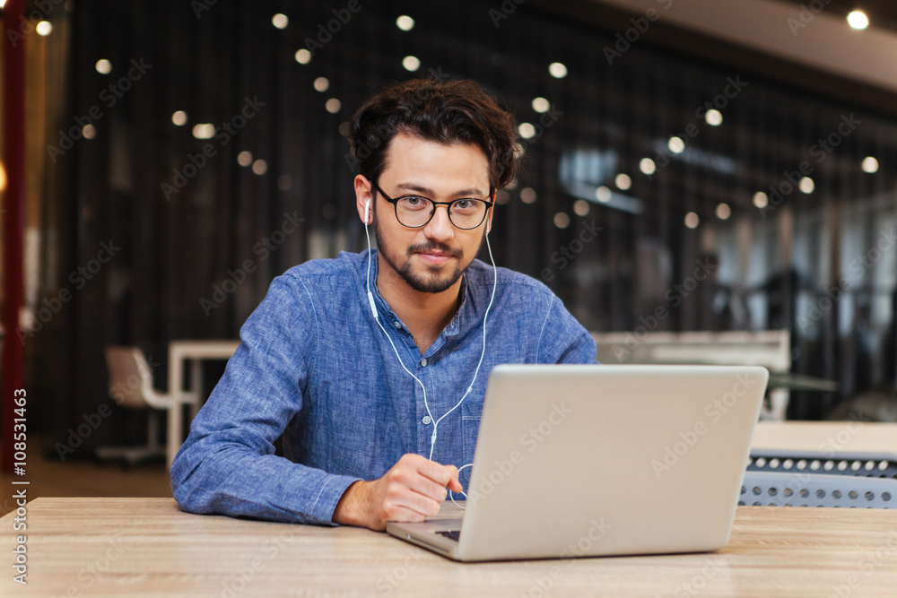 Handsome man sitting at the table with laptop in office Handsome man sitting at the table with laptop in office